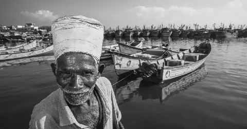Pavadairayan, 60, a migrant laborer known as a "basket man," carries fish in a basket on his head from boats to the auction house at Kasimedu Fishing Harbour in Chennai, India.