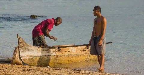 Deux pêcheurs devant leur pirogue sur une plage de Madagascar
