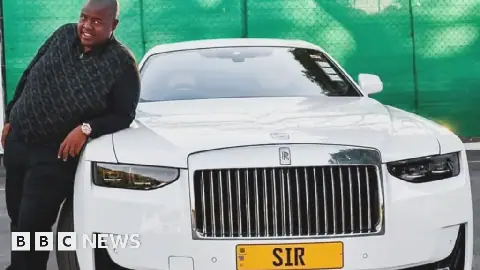 Wicknell Chivayo leans against a white Rolls-Royce with a yellow number plate with the letters "SIR"