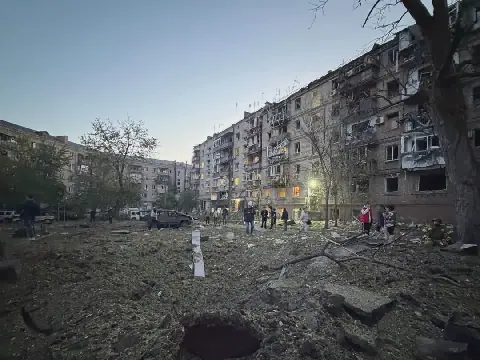 Oekraïense inwoners staan buite hul woonstelgebou wat beskadig is in ’n Russiese aanval op Zaporizjzjia.