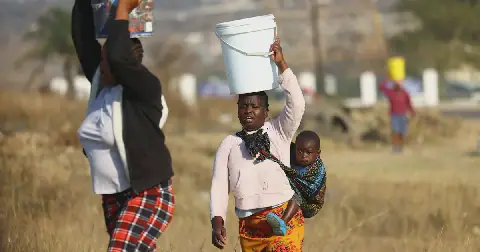 Residents carry buckets filled with water collected from a nearby filling station in Olievenhoutbosch, north of Johannesburg, on August 7 2026. Picture: Reuters/Siphiwe Sibeko